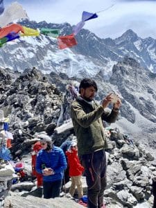 A trekker trying to capture a photo of mountains after a long day difficult treks in Nepal